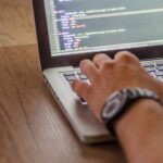 Close-up of a person coding on a laptop, showcasing web development and programming concepts.