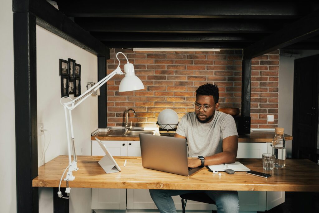 pexels photo 5198249 5198249 A man working from home at a desk with laptop, lamp, and workspace essentials.