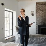 A confident real estate agent inspecting a modern home's interior with fireplace and large windows.
